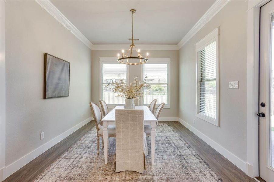 Spacious room featuring wood-finish flooring, two large windows with blinds, and an overhead chandelier