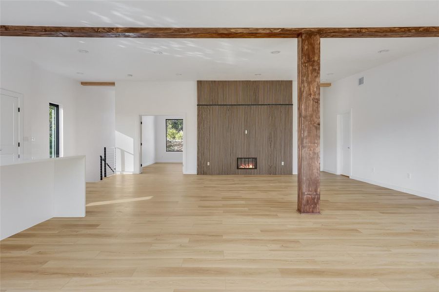Unfurnished living room featuring a fireplace, light wood-type flooring, and beam ceiling Unfurnished living room featuring a fireplace, light wood-type flooring, and beam ceiling