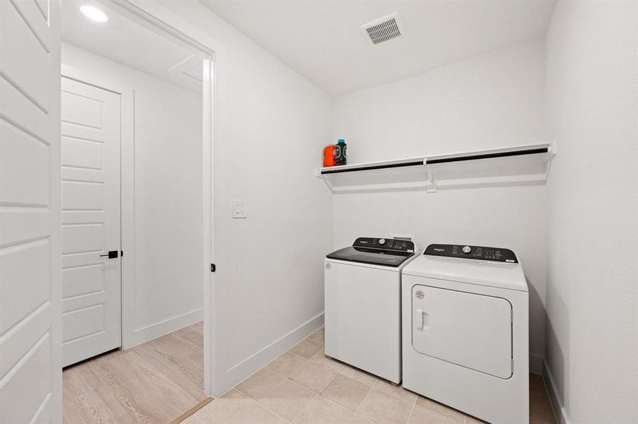 Dedicated laundry area featuring a white built-in shelf, overhead lighting, and tile flooring Dedicated laundry area featuring a white built-in shelf, overhead lighting, and tile flooring