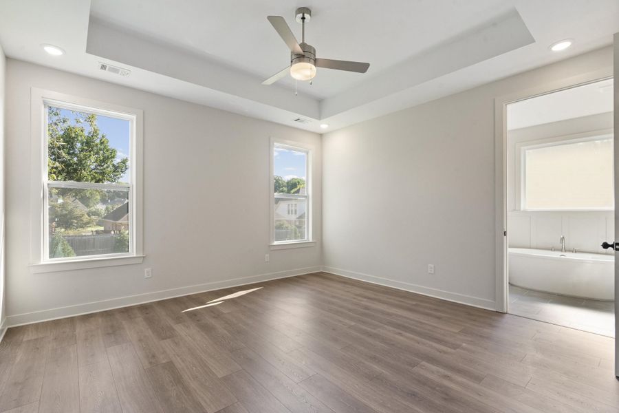 Recessed lighting, wood-finish flooring, and a ceiling fan complement the tray ceiling Recessed lighting, wood-finish flooring, and a ceiling fan complement the tray ceiling