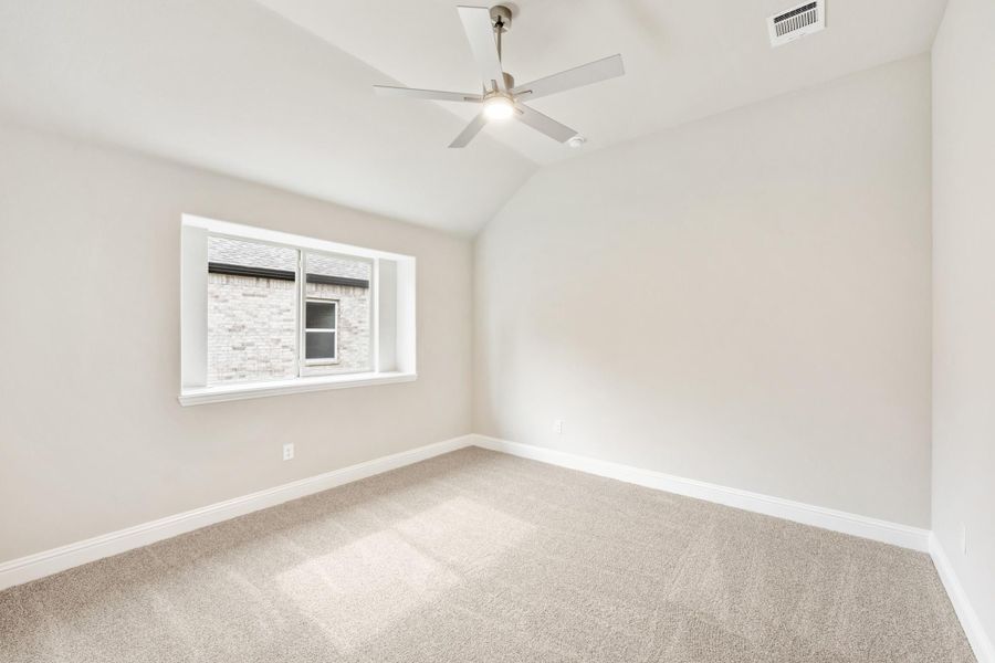 Empty bedroom with vaulted ceiling, ceiling fan, carpet flooring, and a single window