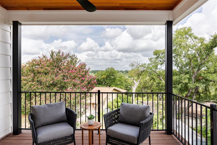 A private balcony with a wood ceiling and elegant iron railing, complete with a ceiling fan, offers a tranquil outdoor space to unwind in style.