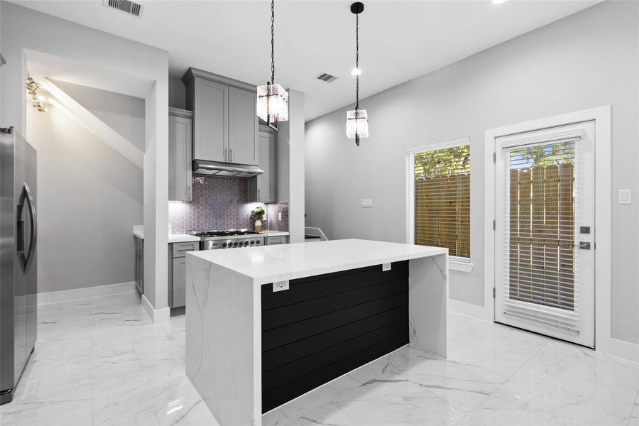 Your kitchen is the heart of the home, designed to feel both polished and practical with a dramatic waterfall island that anchors the space. Soft gray cabinetry, statement pendant lighting, and marble-look flooring give you a clean, upscale look, while the open sightlines to the stairwell keep everything connected and easy to live in. Your kitchen is the heart of the home, designed to feel both polished and practical with a dramatic waterfall island that anchors the space. Soft gray cabinetry, statement pendant lighting, and marble-look flooring give you a clean, upscale look, while the open sightlines to the stairwell keep everything connected and easy to live in.