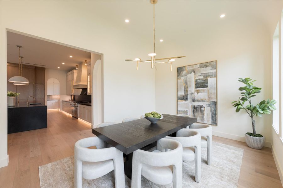 This open dining room offers a seamless visual connection to the kitchen, showcasing a sophisticated interplay of curves, textures, and warm tones. The barrel-vaulted ceiling, sculptural brass chandelier, and European white oak flooring echo the kitchen’s refined materiality—anchored by the custom plaster vent hood and ambient lighting that ties both spaces together. This open dining room offers a seamless visual connection to the kitchen, showcasing a sophisticated interplay of curves, textures, and warm tones. The barrel-vaulted ceiling, sculptural brass chandelier, and European white oak flooring echo the kitchen’s refined materiality—anchored by the custom plaster vent hood and ambient lighting that ties both spaces together.