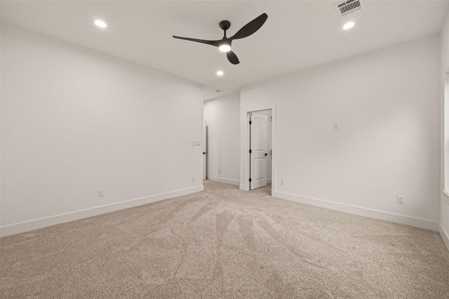 This room features plush carpeting, white walls, recessed lighting, and a modern ceiling fan. It has a clean, spacious feel with a door leading to another area, ideal for a bedroom or office. This room features plush carpeting, white walls, recessed lighting, and a modern ceiling fan. It has a clean, spacious feel with a door leading to another area, ideal for a bedroom or office.
