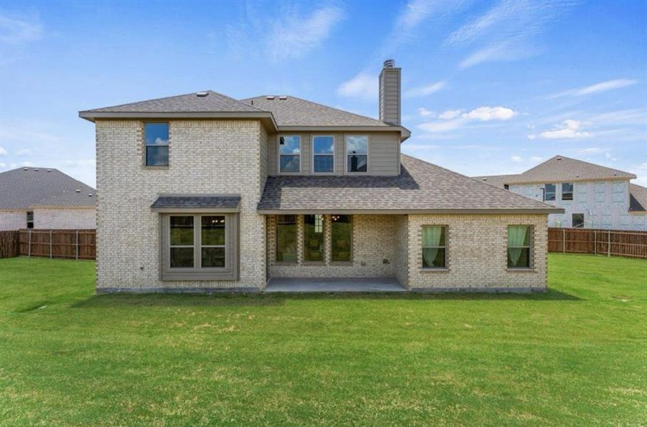 Rear view of property featuring a lawn and a patio