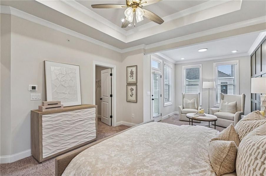 Bedroom featuring carpet, ornamental molding, a ceiling fan, and a tray ceiling