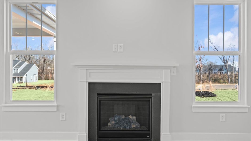 Elegant family room featuring fireplace, hardwood flooring, large windows, and thoughtful architectural detail