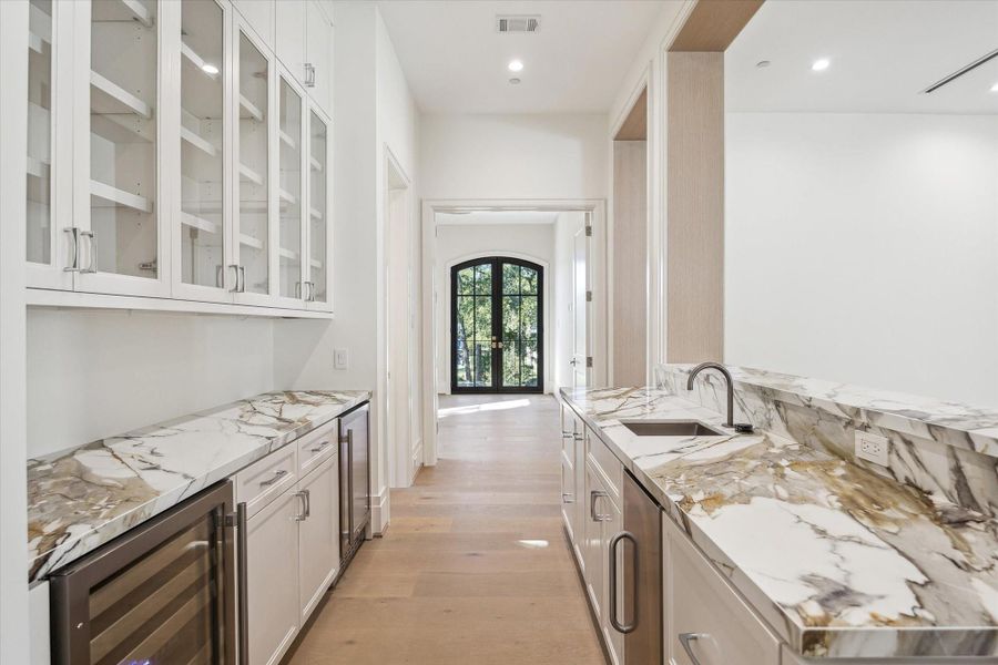 Second-floor refreshment area pairs style and function with a wine cooler, beverage cooler, ice maker, sink, and generous cabinetry.