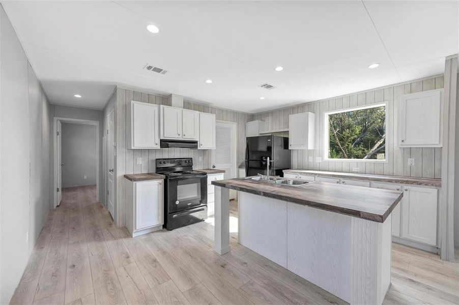 Kitchen featuring visible vents, light wood-style flooring, black appliances, under cabinet range hood, and wood counters