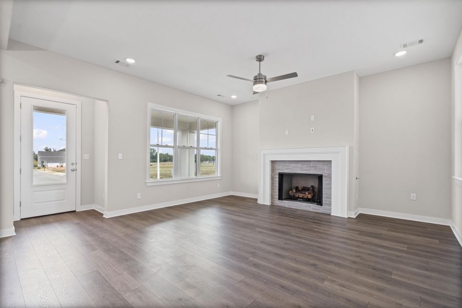 Unfurnished living room featuring a brick fireplace, dark wood finished floors, recessed lighting, and ceiling fan