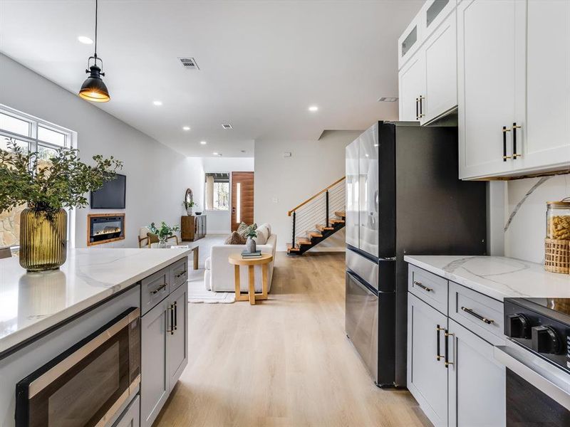 Modern kitchen featuring light-toned cabinetry, stainless steel appliances, quartz countertops, a built-in microwave, and an open concept layout Modern kitchen featuring light-toned cabinetry, stainless steel appliances, quartz countertops, a built-in microwave, and an open concept layout