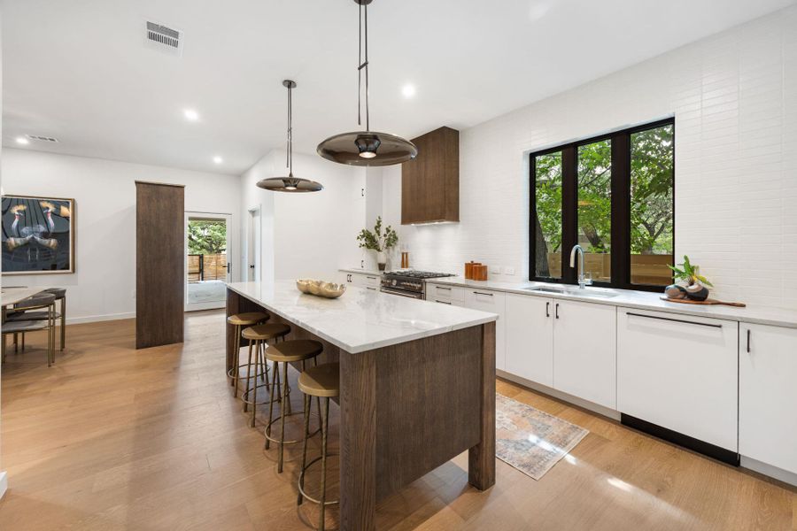 Kitchen with white cabinetry, dark brown cabinets, light stone countertops, pendant lighting, and recessed lighting