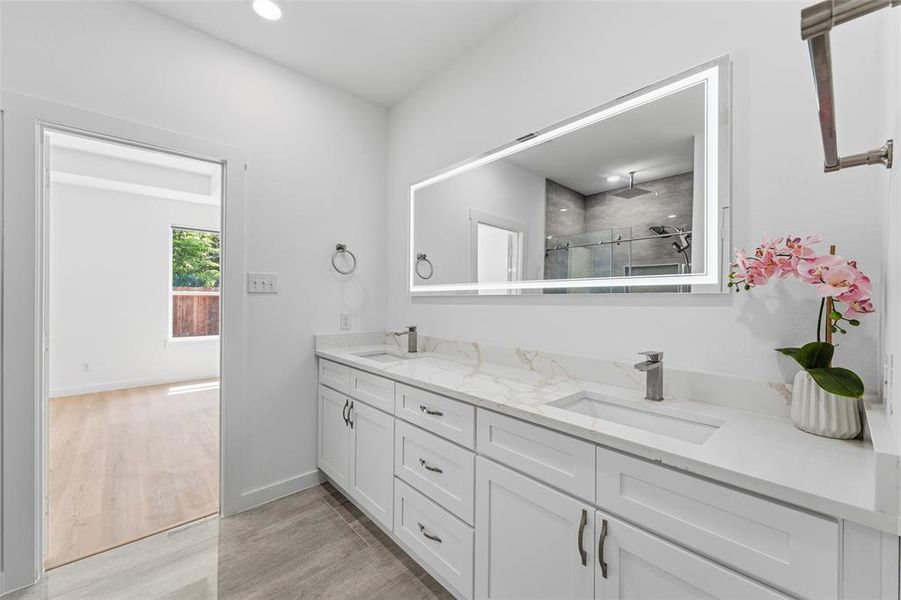 Bathroom featuring a dual vanity with white cabinetry, integrated sinks, and light-toned countertops