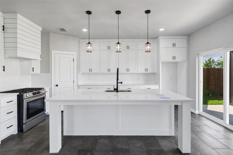 Kitchen with stainless steel gas stove, a sink, wall chimney exhaust hood, white cabinetry, and recessed lighting