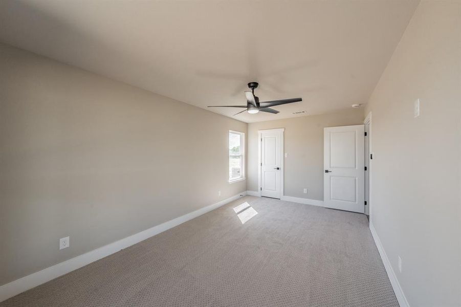 Unfurnished bedroom with carpet flooring and a ceiling fan Unfurnished bedroom with carpet flooring and a ceiling fan