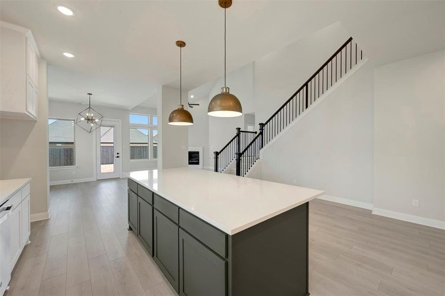 Dual tone kitchen with two tone color scheme, light wood finished floors, a center island, a chandelier, and dishwasher