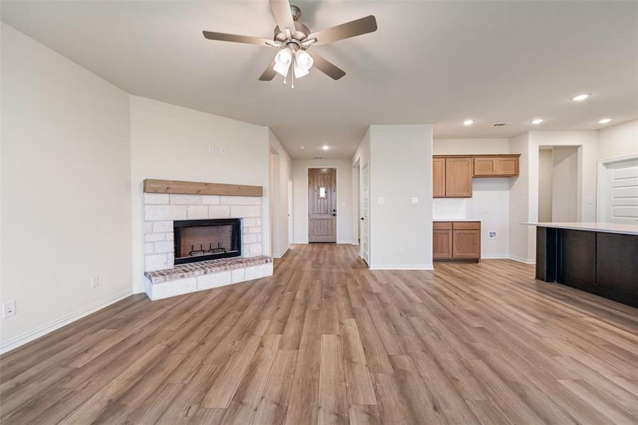 Unfurnished living room featuring light wood-type flooring, recessed lighting, a stone fireplace, and a ceiling fan