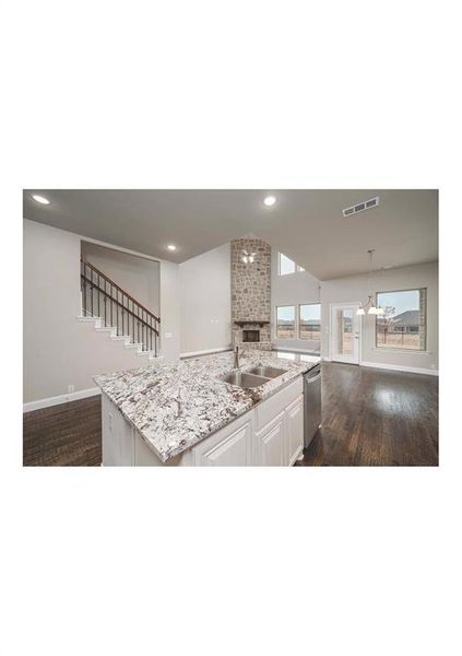 Kitchen with dishwasher, sink, an island with sink, vaulted ceiling, and white cabinets