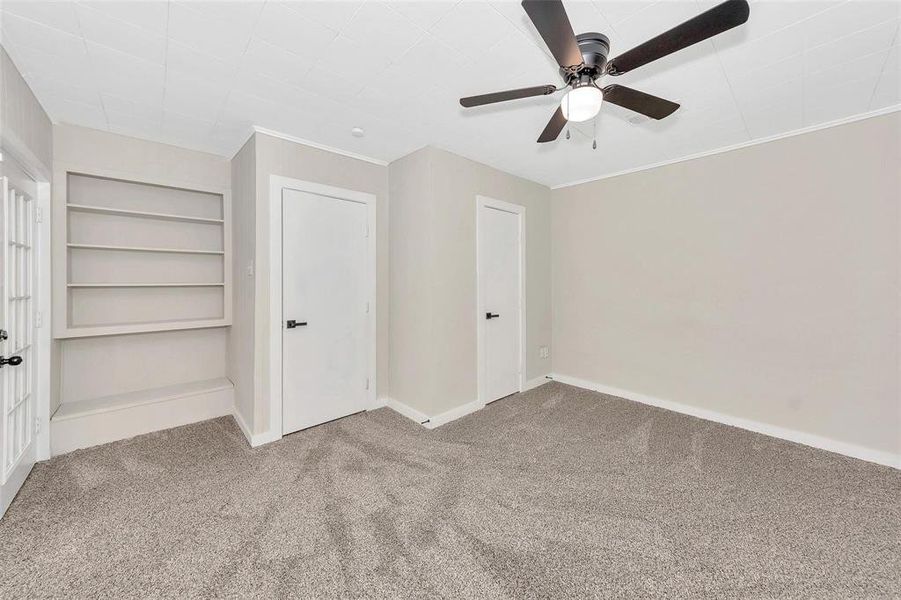 Unfurnished bedroom featuring carpet flooring, a ceiling fan, and crown molding Unfurnished bedroom featuring carpet flooring, a ceiling fan, and crown molding