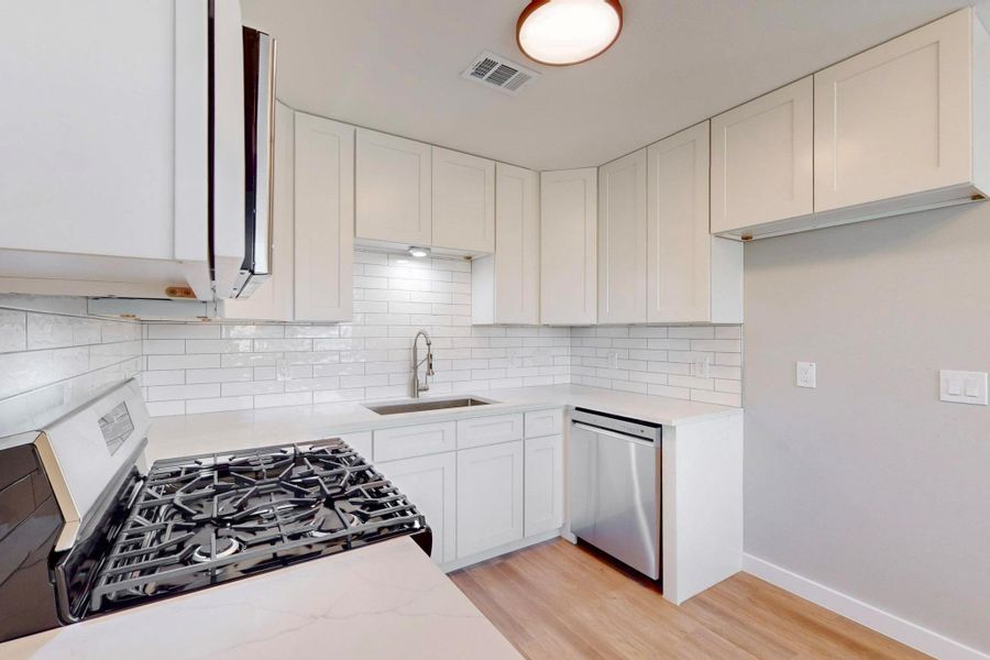 Kitchen featuring new  gas range, built in microwave, quartz counter tops and shaker style cabinets.