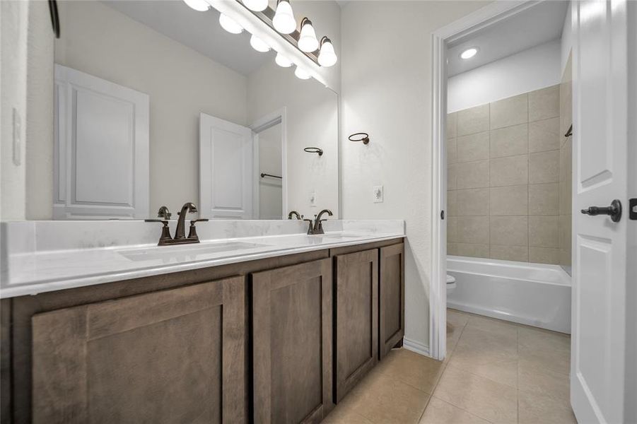 Full bathroom with double vanity, light tile patterned floors, and washtub / shower combination Full bathroom with double vanity, light tile patterned floors, and washtub / shower combination
