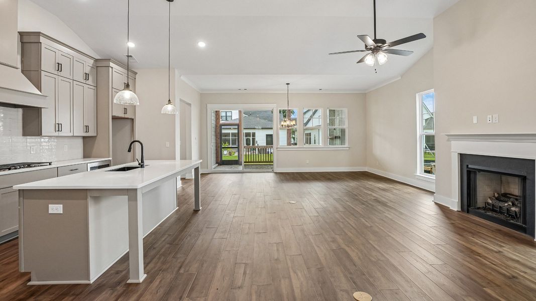 Open Concept layout with kitchen, staircase, access to screened in porch, and living room with fireplace