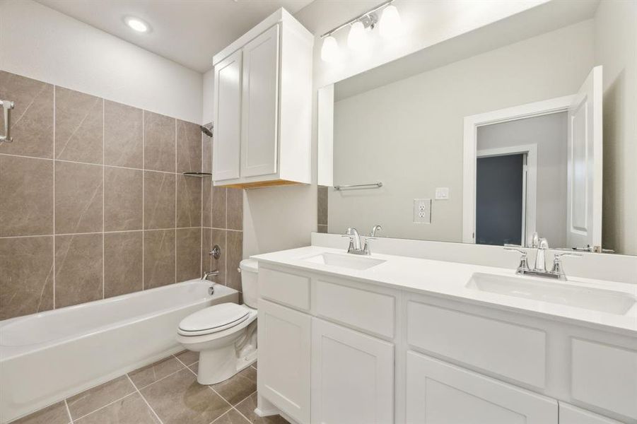 Full bathroom with vanity, toilet, tiled shower / bath combo, and tile patterned flooring