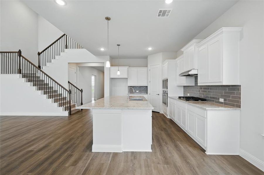 Kitchen featuring visible vents, appliances with stainless steel finishes, dark wood-type flooring, under cabinet range hood, and a sink