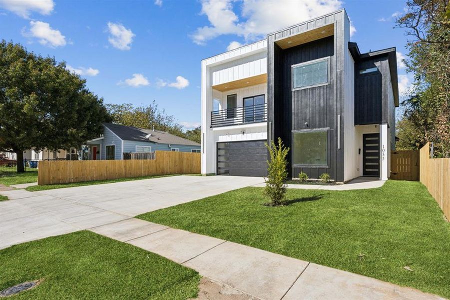 Contemporary house featuring a balcony, concrete driveway, and board and batten siding