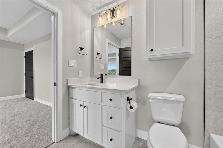 Bathroom featuring a white vanity with a light-colored countertop, matte black faucet, and a contemporary light fixture