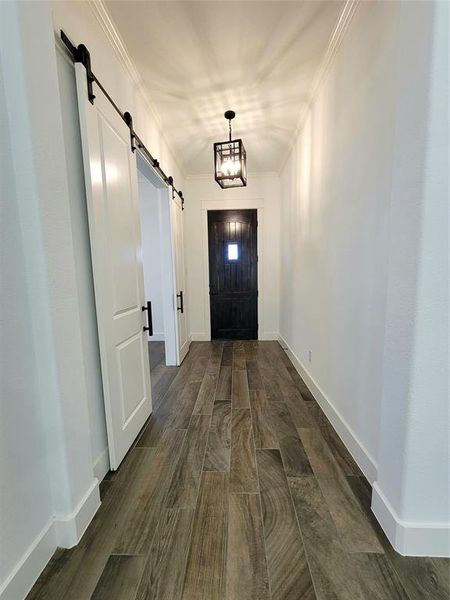 Entryway featuring a barn door to the office with 
ornamental molding