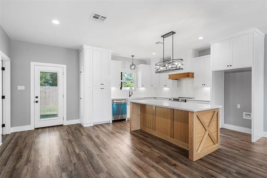 Kitchen featuring stainless steel dishwasher, dark wood-type flooring, backsplash, light countertops, and white cabinets