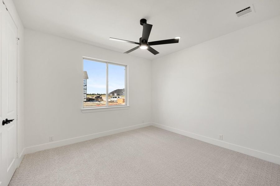 Empty bedroom with white walls, carpet flooring, black ceiling fan, and single window