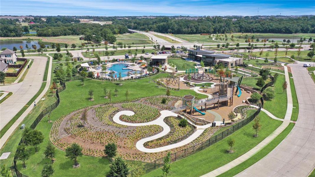 Expansive community park featuring multiple play structures, a large swimming pool, and dedicated recreation buildings
