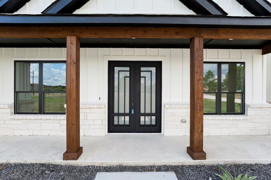 Doorway to property with board and batten siding and a porch