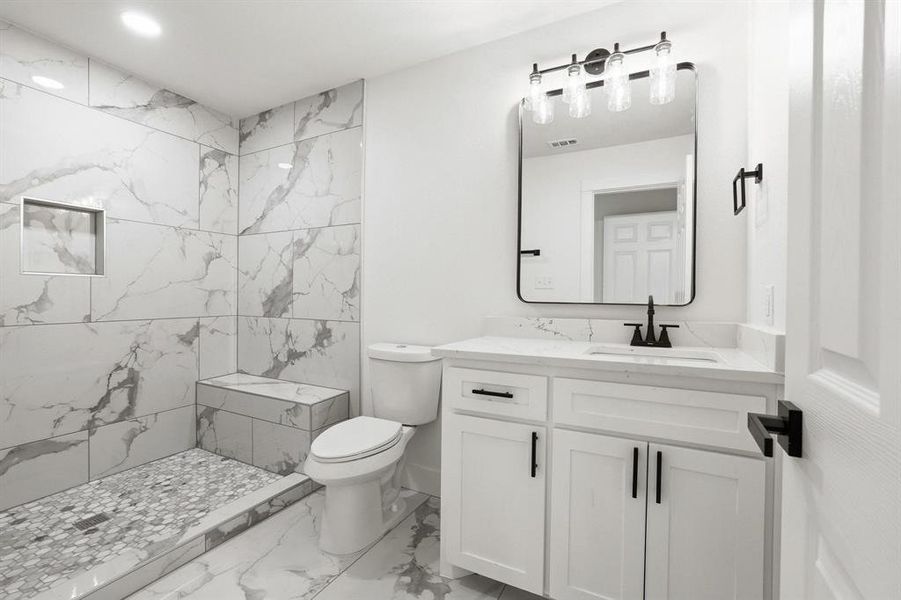 Bathroom featuring a standing shower with a tiled bench, a recessed shower niche, and mosaic tile flooring Bathroom featuring a standing shower with a tiled bench, a recessed shower niche, and mosaic tile flooring