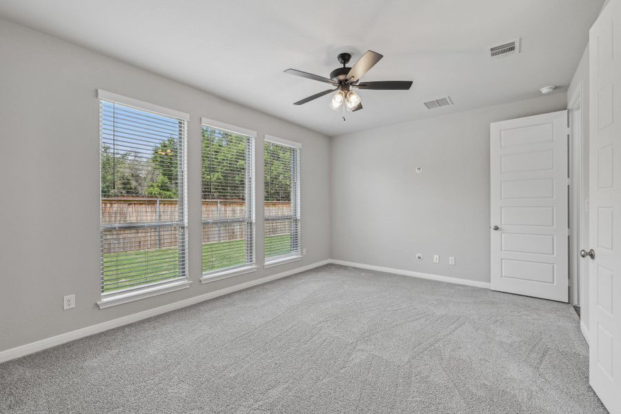 Carpeted empty room with ceiling fan and baseboards Carpeted empty room with ceiling fan and baseboards