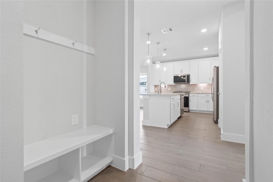 This dedicated area features a custom built-in bench with hooks, perfect for organizing coats, bags, and shoes right off the main hallway, keeping the rest of the home tidy.
