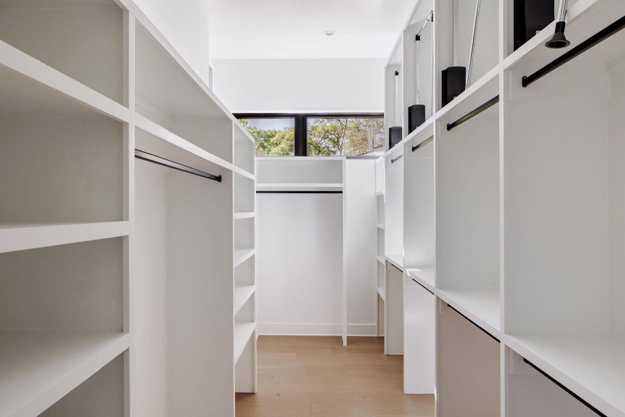 The expansive walk-in closet features custom-built-ins designed for both style and organization. Enjoy natural light as the transom windows allow it to flow in. The expansive walk-in closet features custom-built-ins designed for both style and organization. Enjoy natural light as the transom windows allow it to flow in.