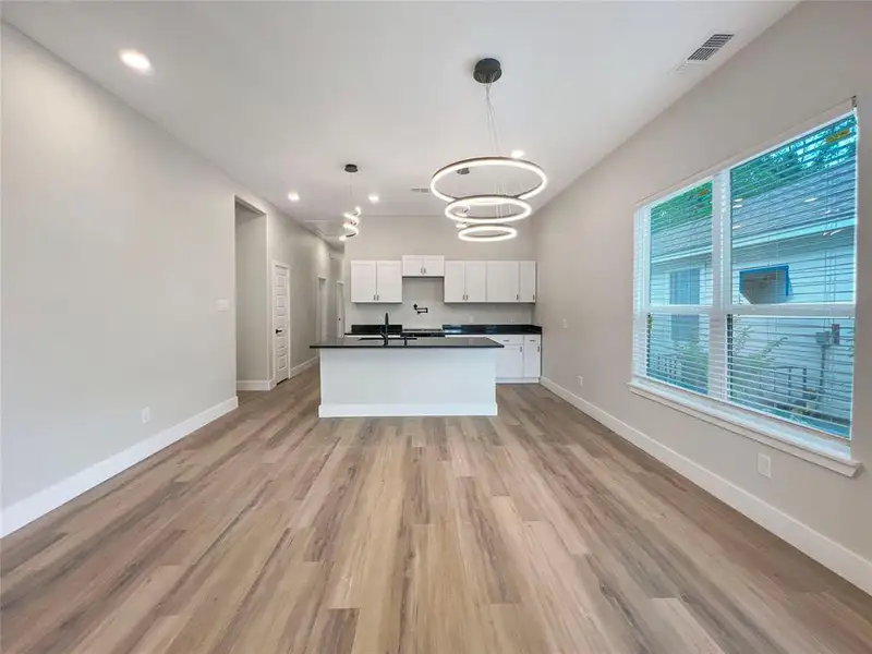 Kitchen featuring white cabinets, dark countertops, baseboards, and a notable chandelier Kitchen featuring white cabinets, dark countertops, baseboards, and a notable chandelier