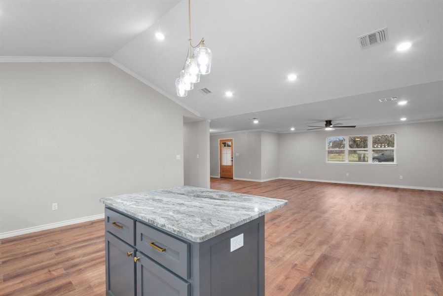 Kitchen featuring ceiling fan, hanging light fixtures, crown molding, lofted ceiling, and a kitchen island Kitchen featuring ceiling fan, hanging light fixtures, crown molding, lofted ceiling, and a kitchen island