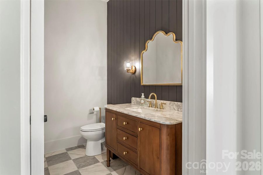 The main level powder room makes a statement with a stunning 48" vanity and warm wood accent wall that adds character and style.