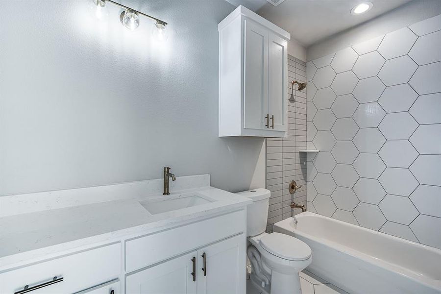 Full bathroom with tile patterned flooring, toilet, vanity, and tiled shower / bath