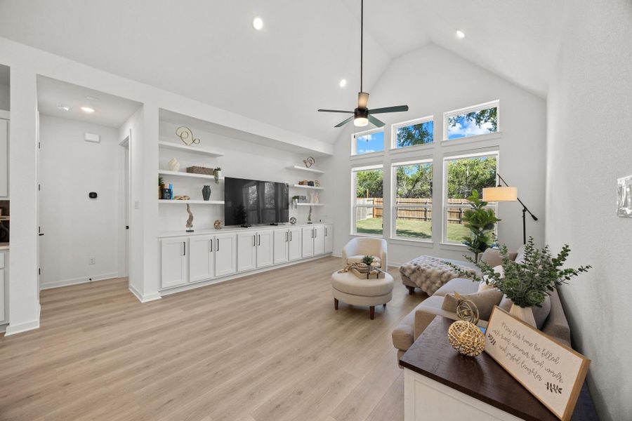 Living room featuring light wood finished floors, a high ceiling, ceiling fan, and recessed lighting