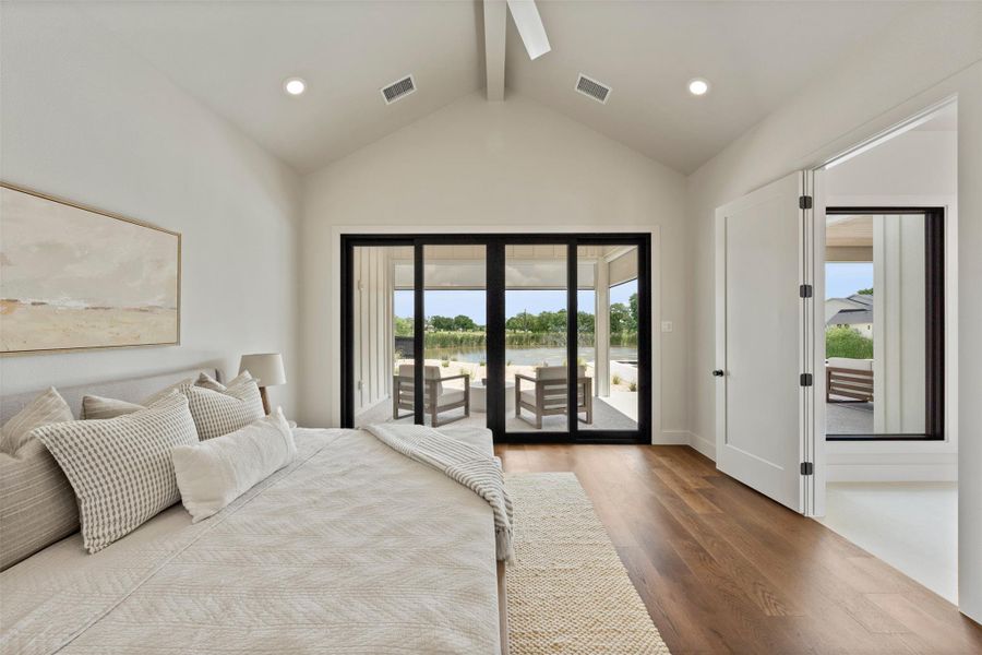 Bedroom with a water view, access to outside, multiple windows, and wood finished floors