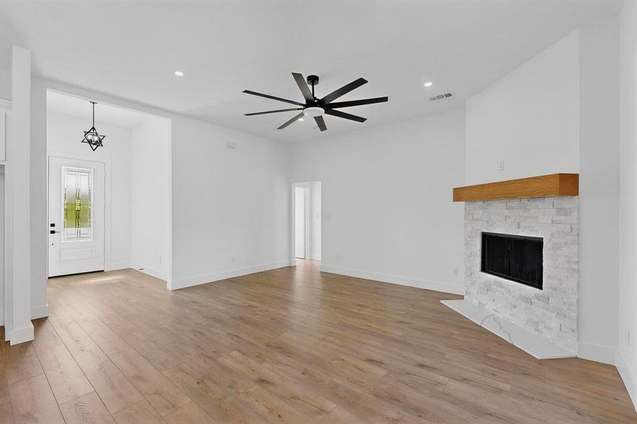 Unfurnished living room featuring light wood-style flooring, a fireplace, recessed lighting, a chandelier, and ceiling fan
