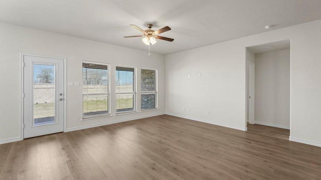 Spacious interior with light wood-style flooring, a ceiling fan with integrated lighting, and white walls