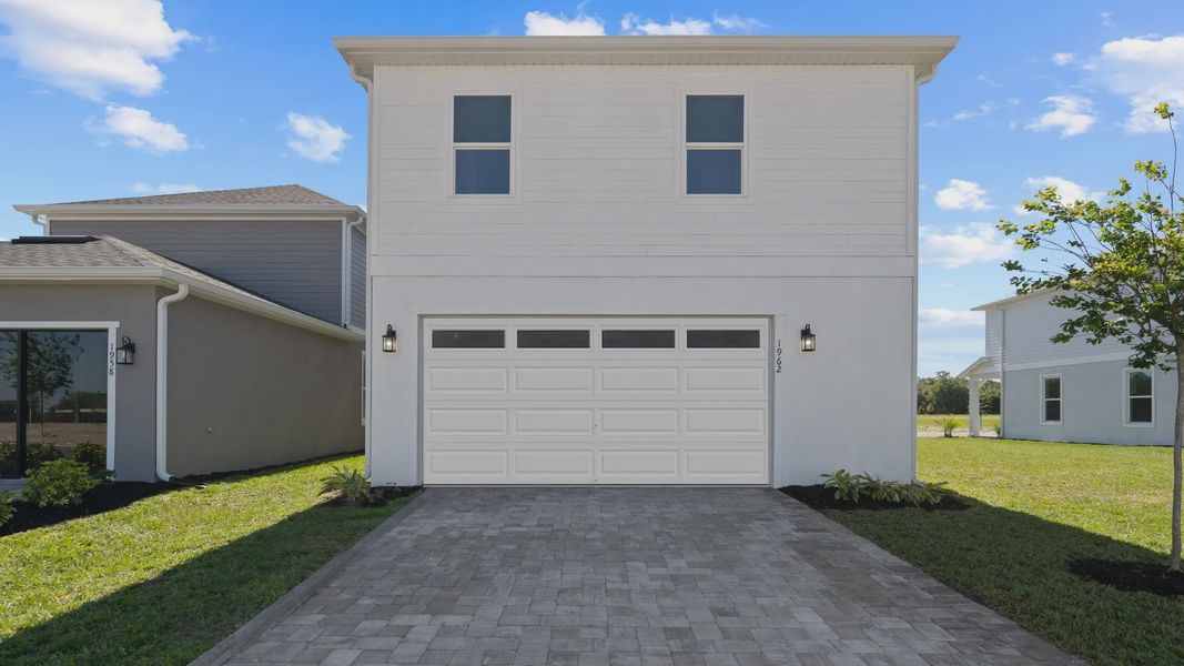 Exterior rear 2 car garage, above retreat with 2 large windows in a DRB Homes Ambersweet model at Trinity Place community. Exterior rear 2 car garage, above retreat with 2 large windows in a DRB Homes Ambersweet model at Trinity Place community.