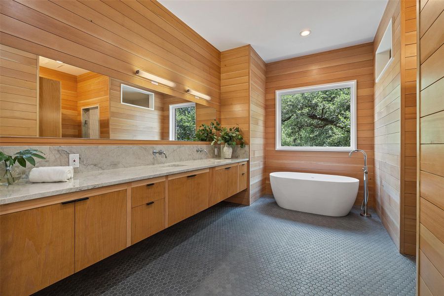 Bathroom with plenty of natural light, double vanity, a freestanding tub, wood walls, and dark tile patterned floors